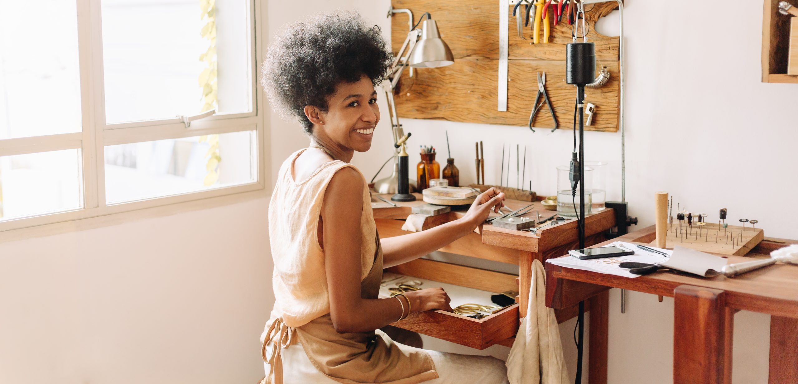 African,Artist,Glancing,Back,While,Working,At,Jewelry,Workshop.,Cheerful African,Artist,Glancing,Back,While,Working,At,Jewelry,Workshop.,Cheerful